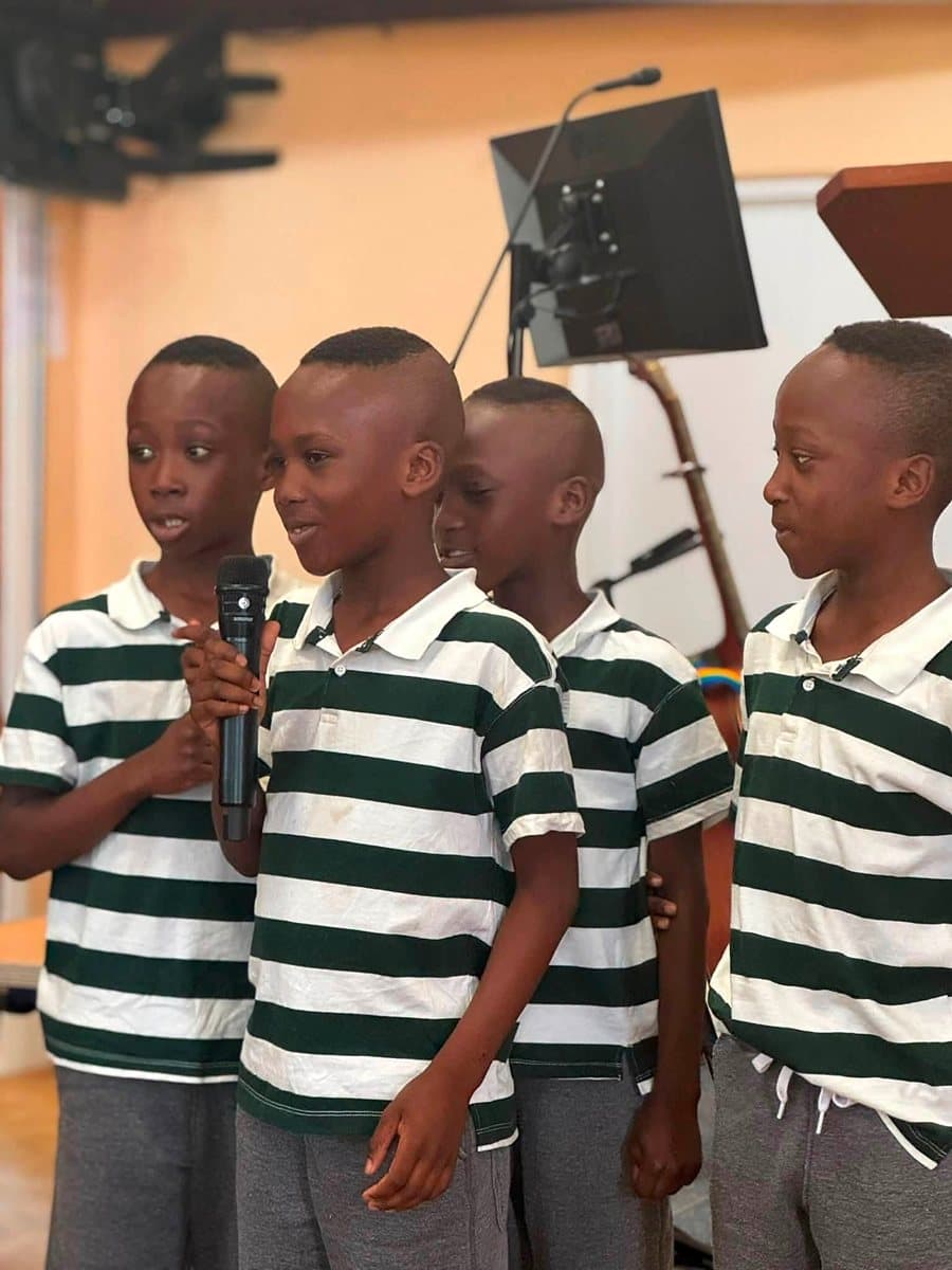 Four boys in matching striped shirts singing together at church