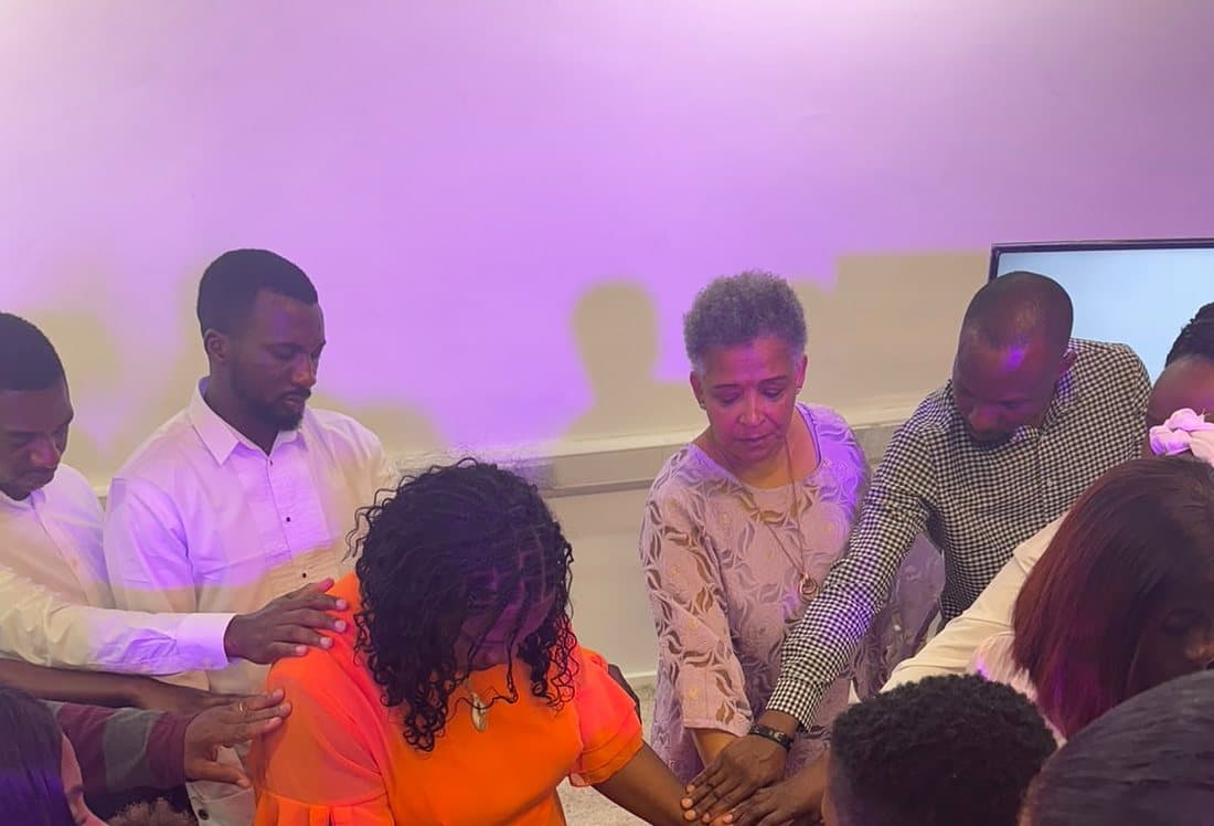 Members of the church gathered in a circle, laying hands on one another in prayer