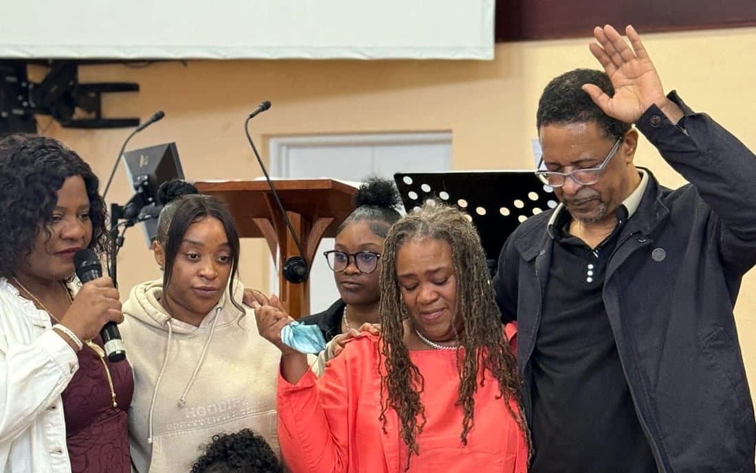 Pastor Catherine and church members praying over a family