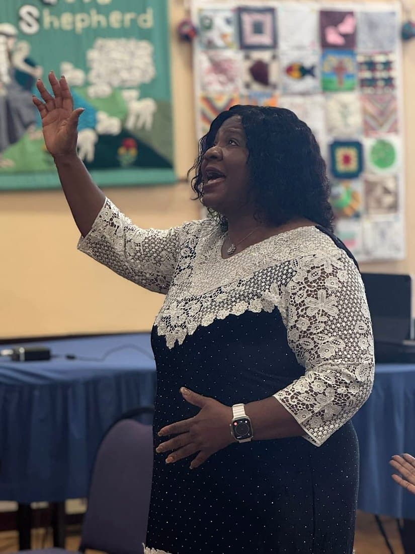 Pastor Catherine worshipping with her hand raised