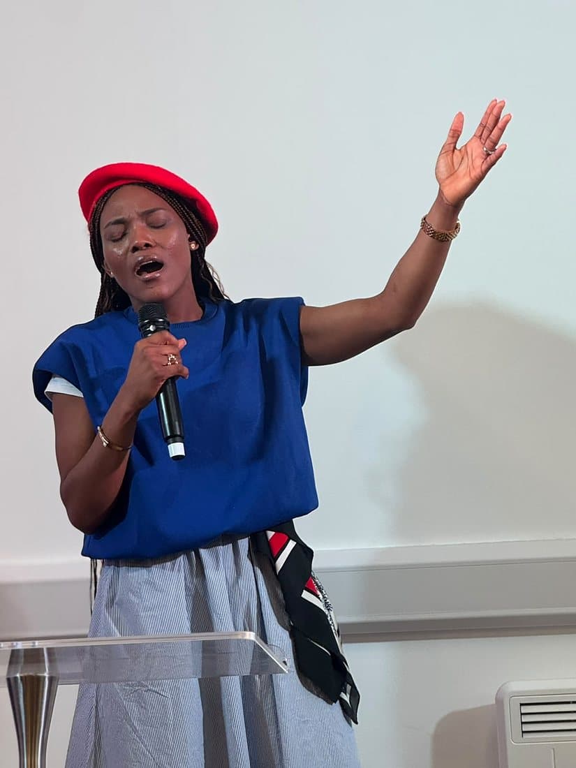 A worship leader singing with eyes closed and hand raised