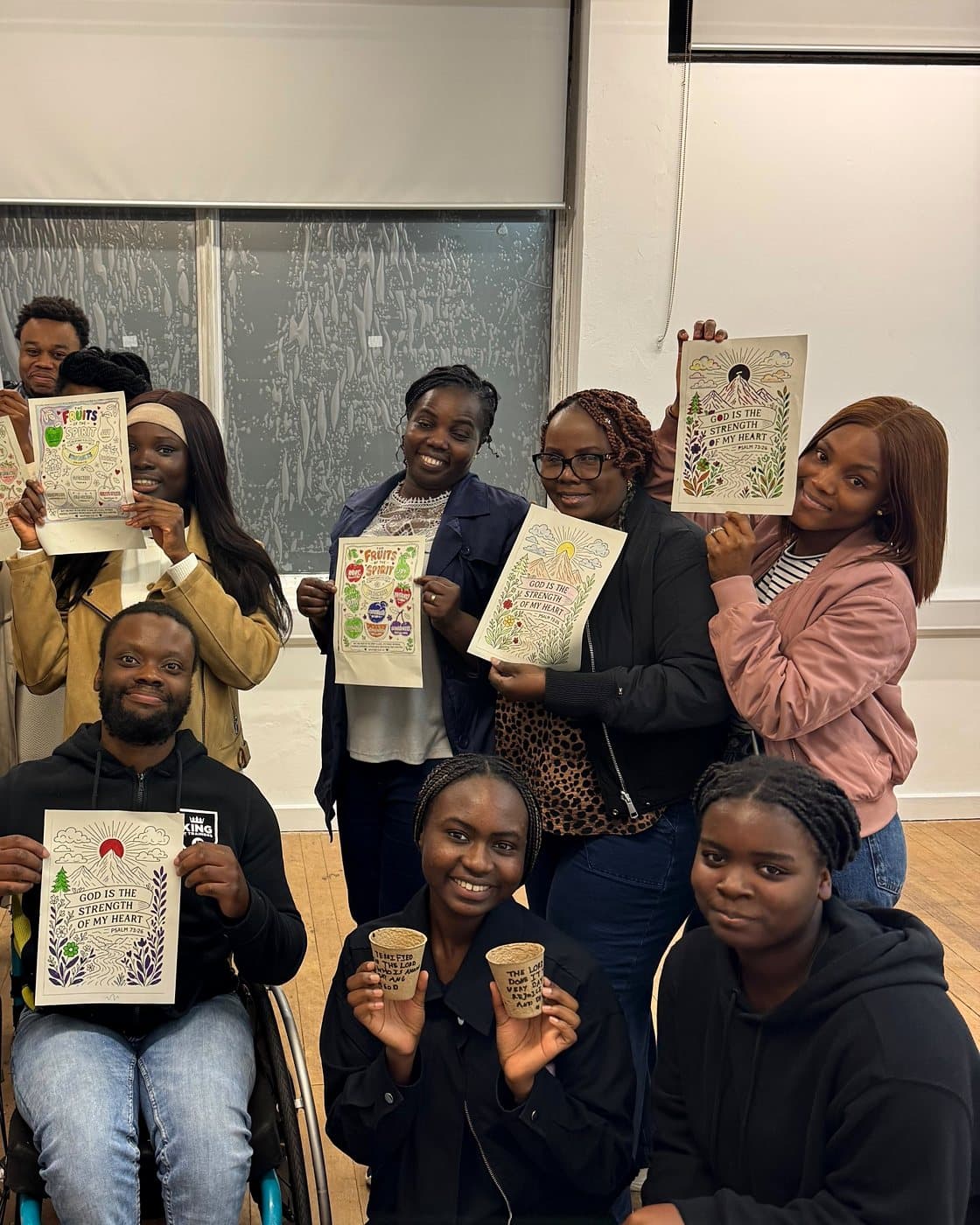 Young people and leaders holding up their Psalm 73:26 colouring sheets and seed pots